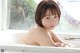 A woman in a bathtub with water droplets on her body.