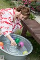 A woman in a red and white kimono playing with colorful balls.