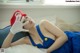 A woman in a blue dress and a red hat laying on a bed.