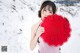 A woman holding a red paper cutout in the snow.