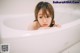 A little girl is sitting in a bathtub looking at the camera.