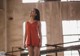 A woman in a red dress standing on a railing.