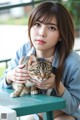 A woman sitting at a table holding a cat.