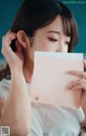 A woman holding a pink envelope in front of her face.