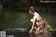 A woman sitting on a rock in the water.