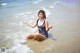 A woman in a bathing suit sitting in the water.