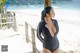 A woman in a black swimsuit standing on a beach.