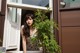 A woman leaning against a window sill next to a plant.